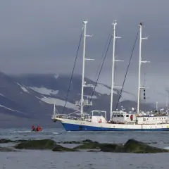 Statek badawczy "Oceania" na tle ośnieżonych gór. Mała łódź z ludźmi zbliża się do niego. Ciekawe, czy na morzu jest zasięg.