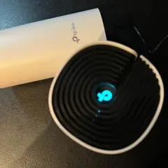 Dwa urządzenia TP-Link, jedno białe, drugie czarne z niebieskim logo. Chcesz wiedzieć, jak zmienić hasło do wifi?
