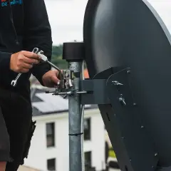 Technik reguluje antenę satelitarną, by jak najlepiej ustawić sygnał.