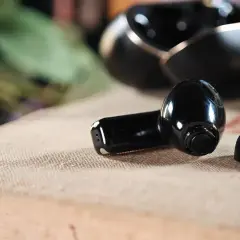 Czarne słuchawki Huawei leżą obok etui. Dowiedz się, jak podłączyć słuchawki Huawei do Samsunga, aby cieszyć się muzyką.