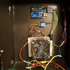 Układ chłodzenia z wentylatorem i radiatorem, sterowany przez Arduino Uno. W tle widać moduł przekaźnika, a całość tworzy system z ogniwem Peltiera.