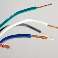 Kolorowe przewody elektryczne, gotowe do podłączenia gniazdka. Widoczne miedziane żyły i izolacje w odcieniach zieleni, bieli, czerni, niebieskiego i różu.
