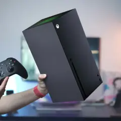 Ręce trzymają czarny kontroler Xbox i konsolę Xbox Series S. Dowiedz się, jak podłączyć drugiego pada do Xbox Series S.