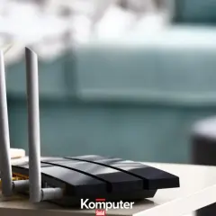 Jak podłączyć dysk do routera? Czarny router z antenkami i żółtym kablem na stoliku, obok doniczka z zieloną rośliną.