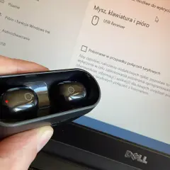 Słuchawki bezprzewodowe w etui, obok ekranu laptopa z ustawieniami USB. Jak podłączyć słuchawki przewodowe do komputera? To proste, wystarczy port.