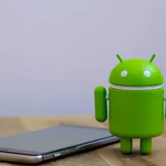 Zielony robot Android obok telefonu, gotowy na aktualizację do android 14.
