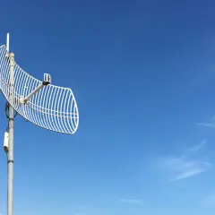 Siatkowa antena telewizyjna na tle błękitnego nieba z chmurami.
