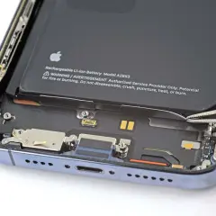 Wymiana baterii iPhone 14 Pro w toku. Pęseta odłącza taśmę baterii.