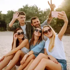 Grupa przyjaciół robi selfie na plaży. Zastanawiasz się, jak sprawdzić, czy roaming jest włączony Plus abonament? Sprawdź to przed wyjazdem!