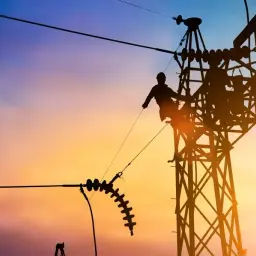 Sylwetki pracowników na tle zachodzącego słońca, pracujących przy linii wysokiego napięcia. W oddali widać łuk elektryczny.