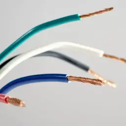 Kolorowe przewody elektryczne, gotowe do podłączenia gniazdka. Widoczne miedziane żyły i izolacje w odcieniach zieleni, bieli, czerni, niebieskiego i różu.