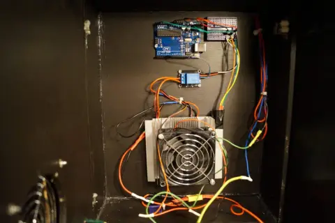 Układ chłodzenia z wentylatorem i radiatorem, sterowany przez Arduino Uno. W tle widać moduł przekaźnika, a całość tworzy system z ogniwem Peltiera.