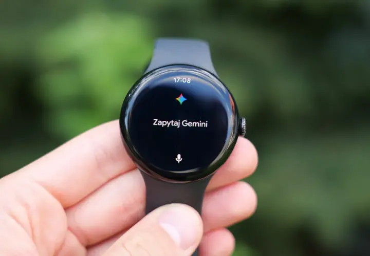 Zegarek z Wear OS na ręce, wyświetla godzinę 17:08 i komunikat "Zapytaj Gemini".