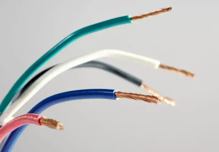 Kolorowe przewody elektryczne, gotowe do podłączenia gniazdka. Widoczne miedziane żyły i izolacje w odcieniach zieleni, bieli, czerni, niebieskiego i różu.