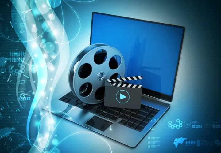 Laptop z kliszą filmową i klapsem, symbolizujące odtwarzanie multimediów. Idealne do obsługi plików dzięki K-Lite Codec Pack.