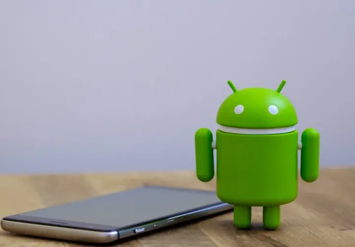 Zielony robot Android obok telefonu, gotowy na aktualizację do android 14.