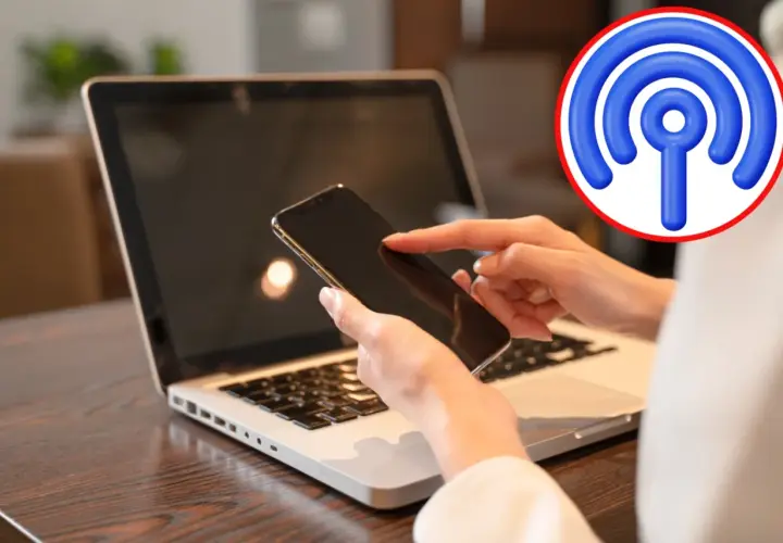 Jak udostępnić internet z telefonu na komputer przez USB? Dłoń z telefonem nad klawiaturą laptopa, symbol Wi-Fi.