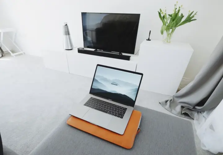 Nowoczesny salon z laptopem przygotowanym do screen mirroring na dużym ekranie telewizora.