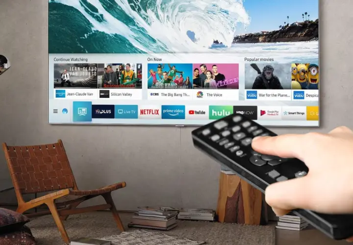 Smart TV z pilotem w dłoni, pokazujący aplikacje streamingowe. Czy smart TV potrzebuje anteny? Nie, jeśli korzystasz z internetu.