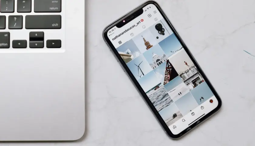 Telefon z Instagramem obok klawiatury laptopa. Dowiedz się, jak połączyć telefon z komputerem przez wifi, by łatwo przesyłać zdjęcia.