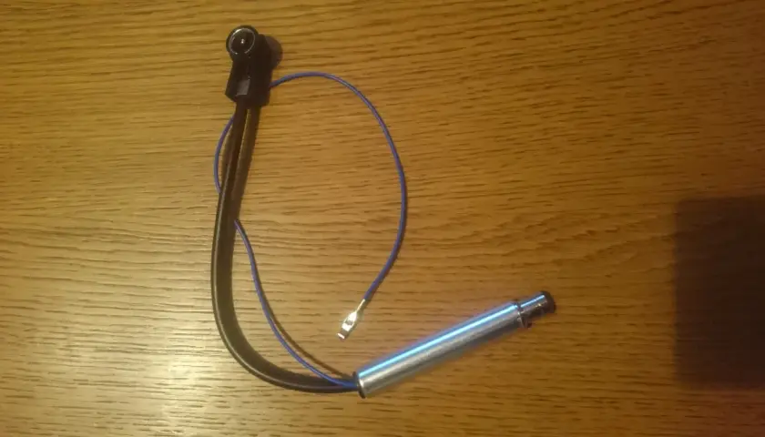 Antena samochodowa z kablem i wtyczką na drewnianym tle.