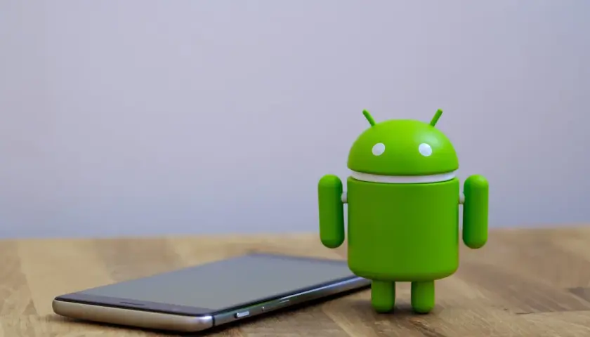 Zielony robot Android obok telefonu, gotowy na aktualizację do android 14.