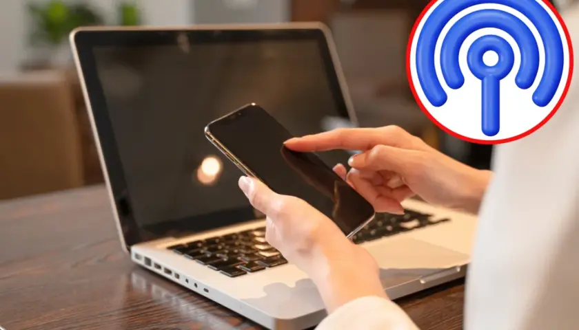 Jak udostępnić internet z telefonu na komputer przez USB? Dłoń z telefonem nad klawiaturą laptopa, symbol Wi-Fi.