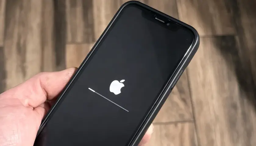 iPhone z logo Apple i paskiem postępu, aktualizacja iOS 26.3 w toku.