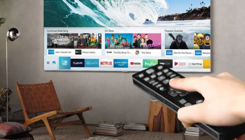 Smart TV z pilotem w dłoni, pokazujący aplikacje streamingowe. Czy smart TV potrzebuje anteny? Nie, jeśli korzystasz z internetu.