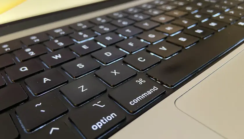 Klawiatura laptopa z podświetlanymi klawiszami. Widoczne litery Q, W, E, A, S, D, Z, X, C, a także klawisze "control", "option" i "command".