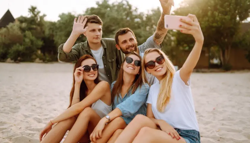 Grupa przyjaciół robi selfie na plaży. Zastanawiasz się, jak sprawdzić, czy roaming jest włączony Plus abonament? Sprawdź to przed wyjazdem!