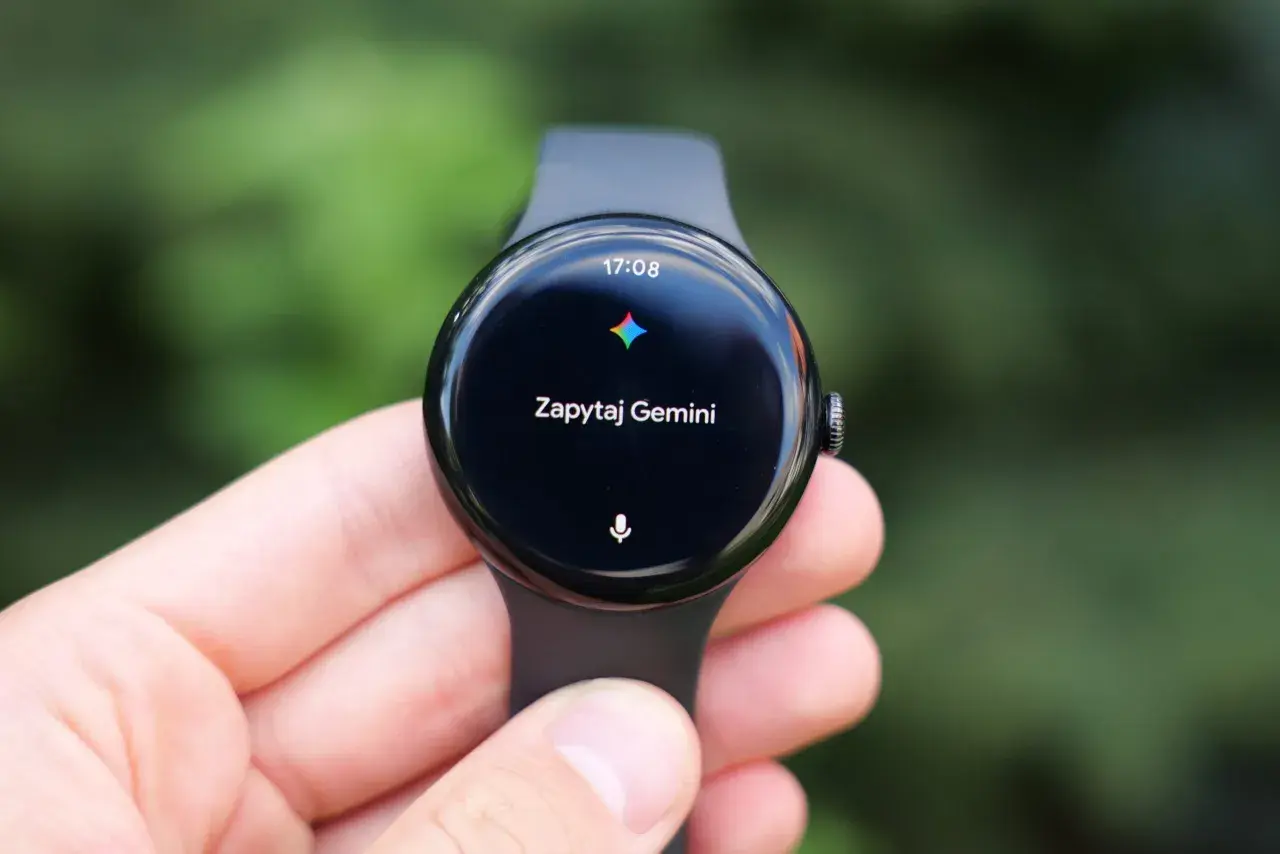 Zegarek z Wear OS na ręce, wyświetla godzinę 17:08 i komunikat "Zapytaj Gemini".