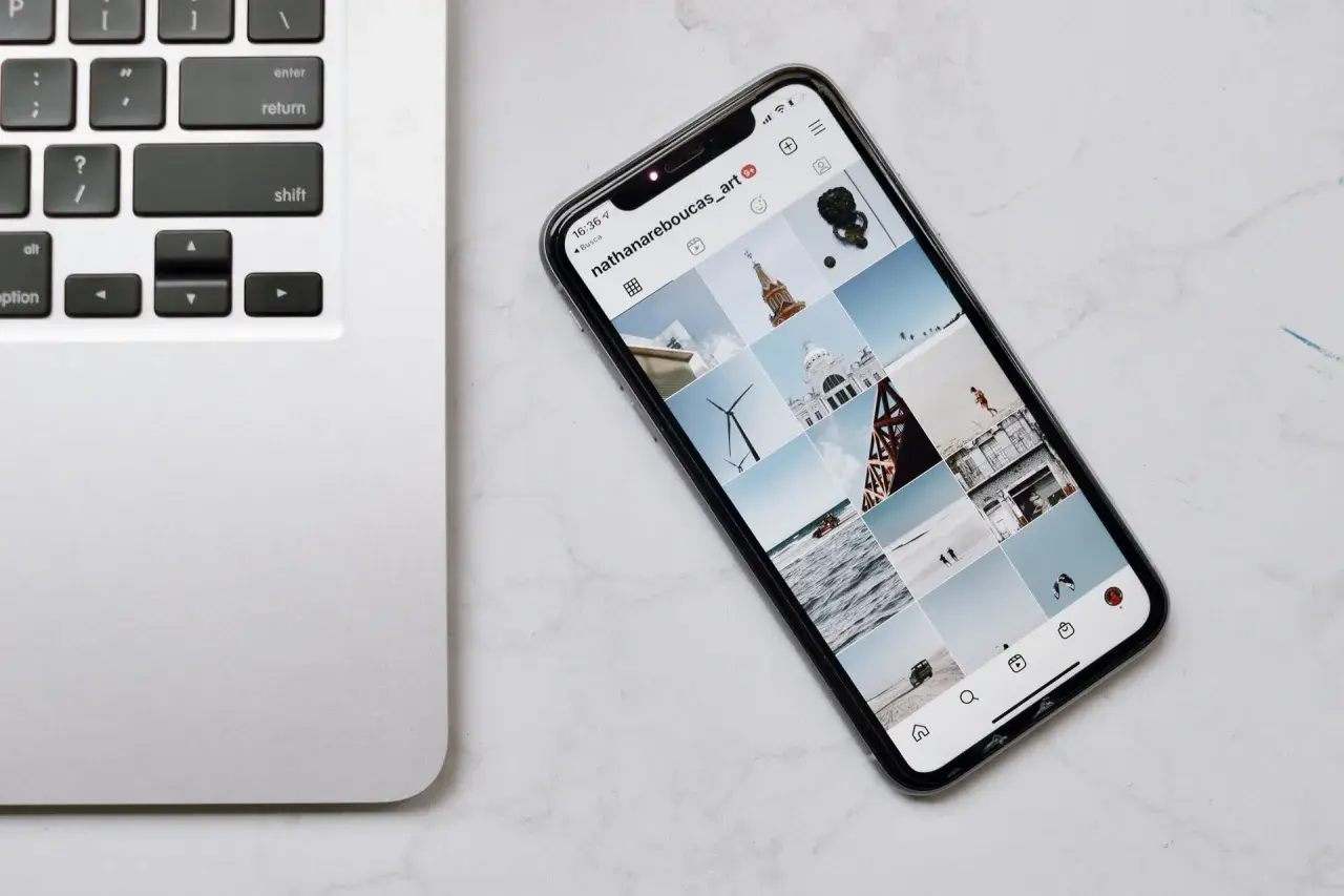 Telefon z Instagramem obok klawiatury laptopa. Dowiedz się, jak połączyć telefon z komputerem przez wifi, by łatwo przesyłać zdjęcia.