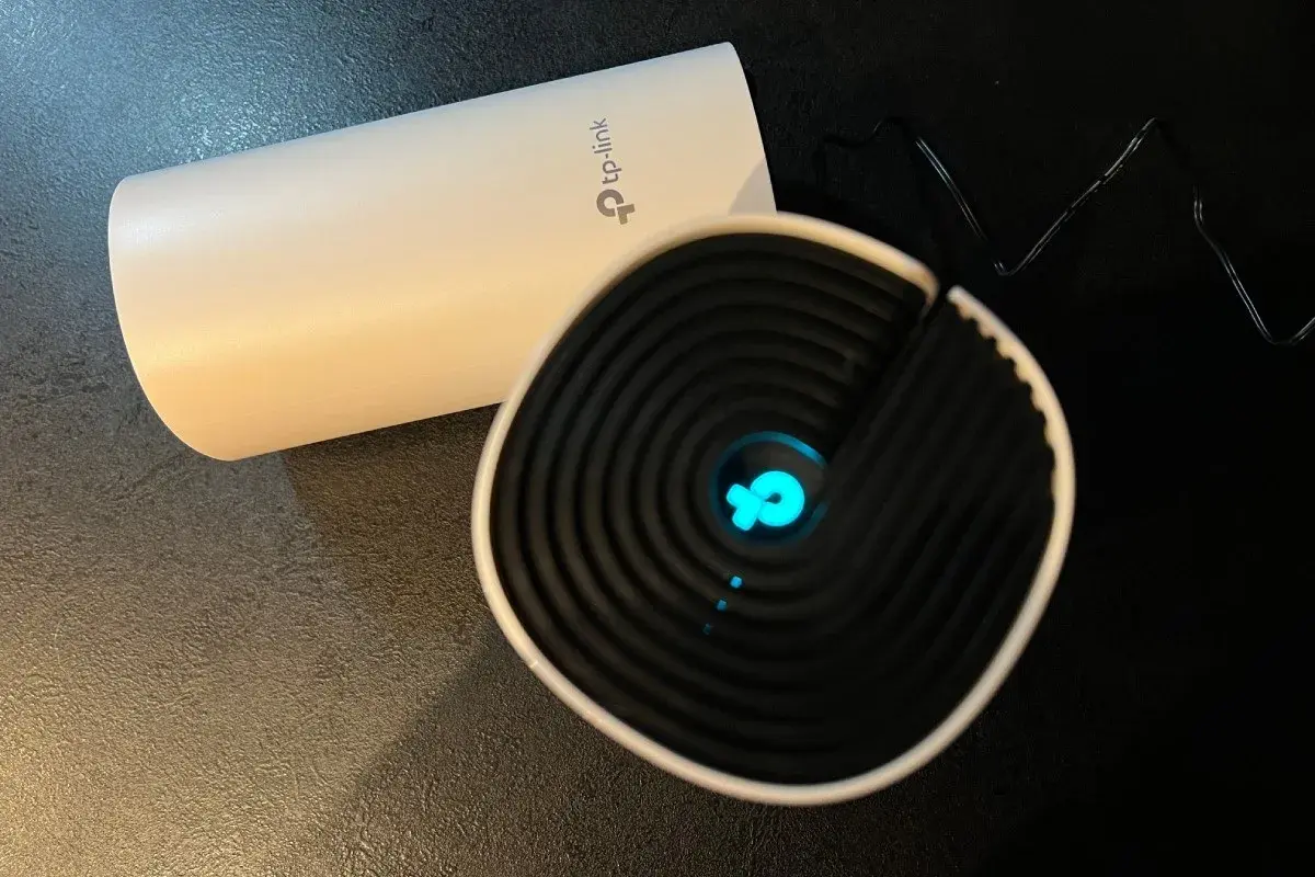 Dwa urządzenia TP-Link, jedno białe, drugie czarne z niebieskim logo. Chcesz wiedzieć, jak zmienić hasło do wifi?