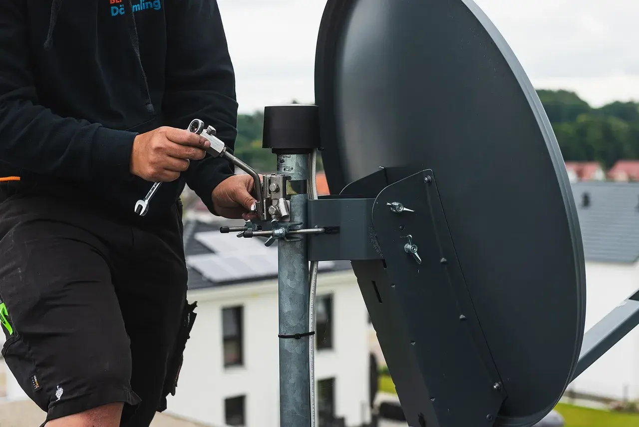 Technik reguluje antenę satelitarną, by jak najlepiej ustawić sygnał.
