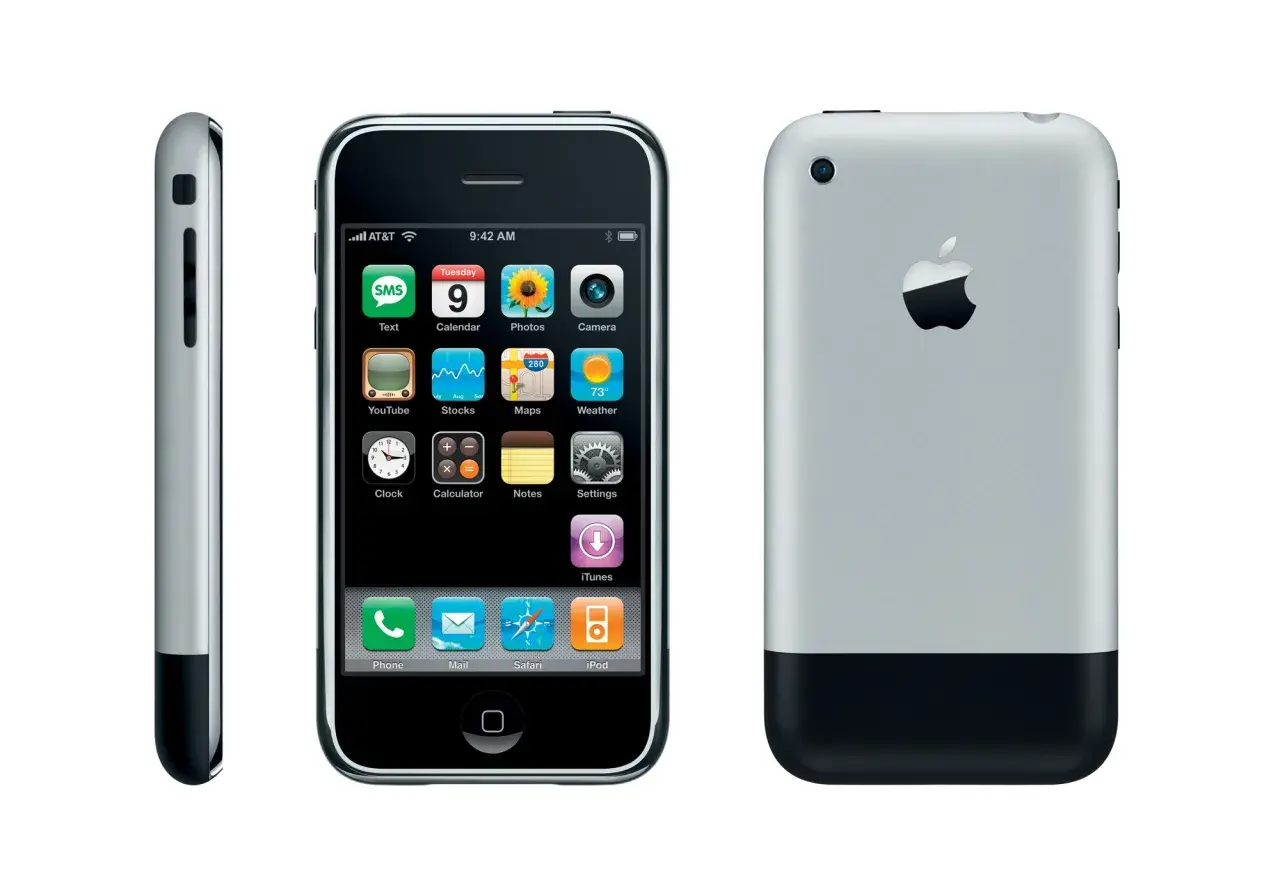 Trzy widoki pierwszego iPhone'a. Widoczny ekran z ikonami aplikacji, bok urządzenia oraz tył z logo Apple.