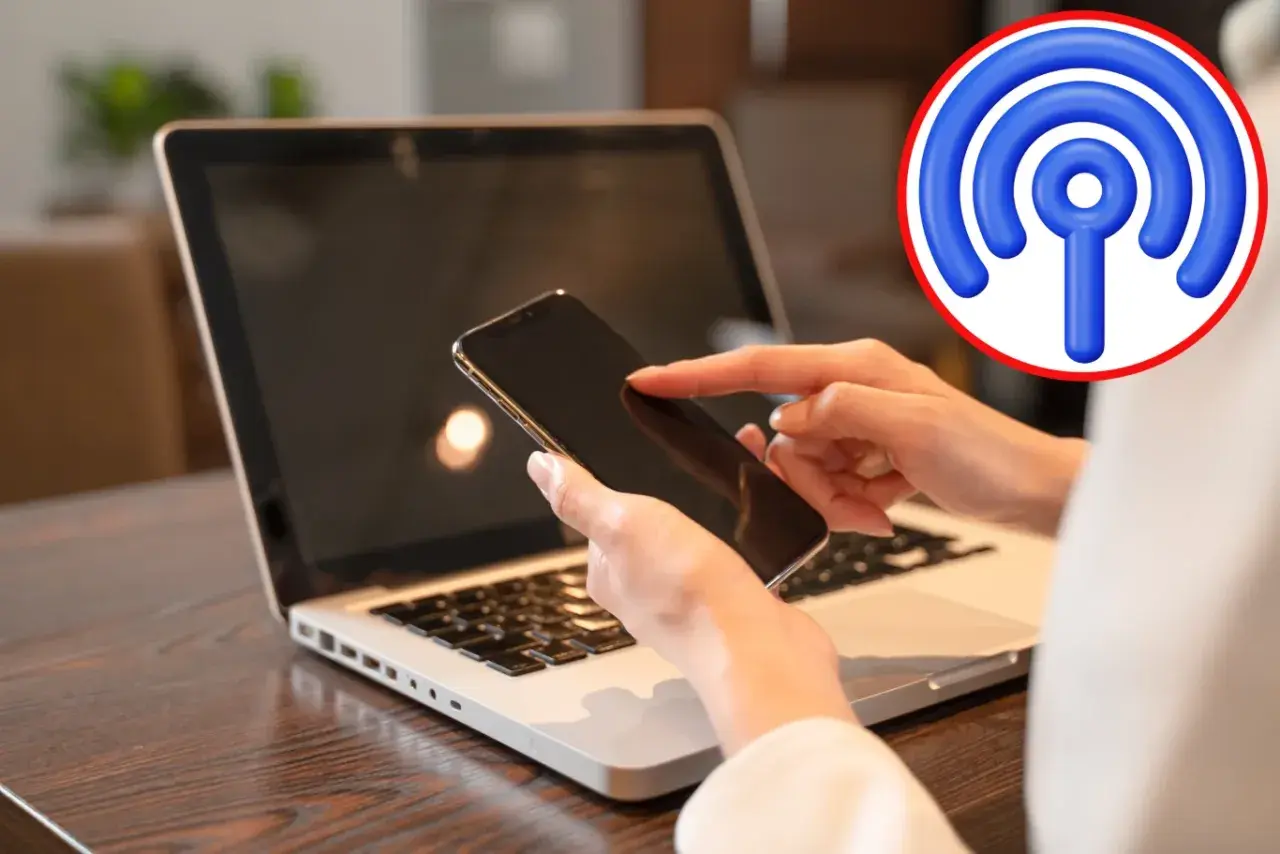 Jak udostępnić internet z telefonu na komputer przez USB? Dłoń z telefonem nad klawiaturą laptopa, symbol Wi-Fi.