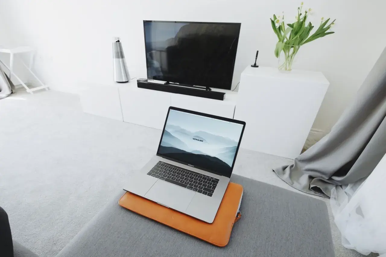 Nowoczesny salon z laptopem przygotowanym do screen mirroring na dużym ekranie telewizora.
