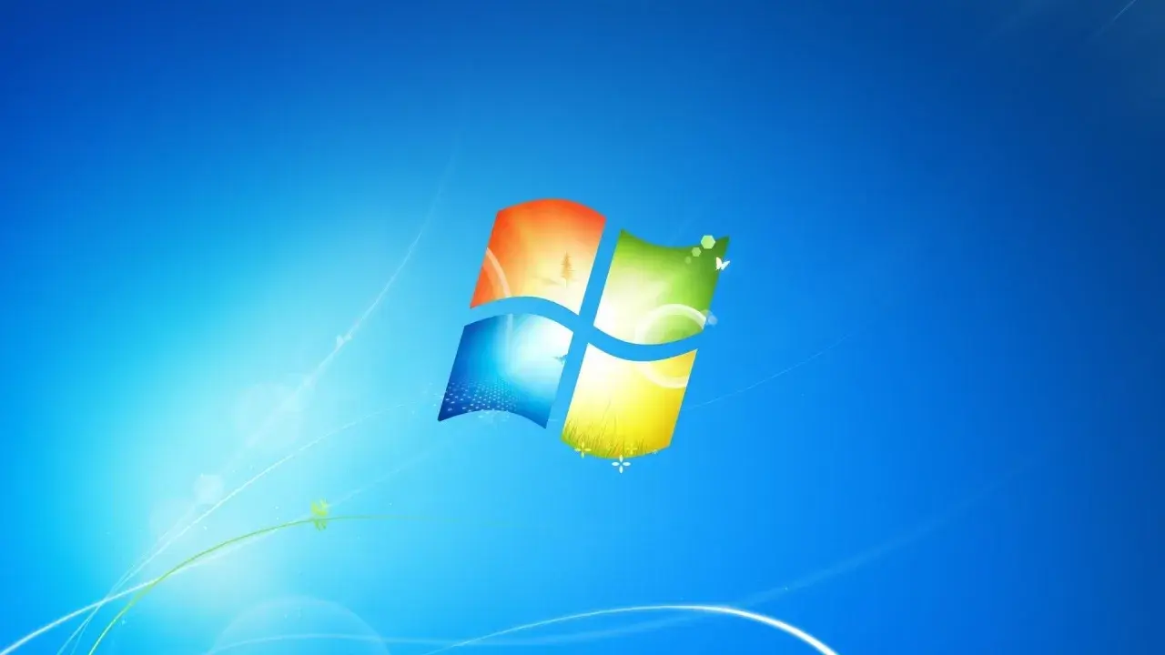 Ikona systemu Windows 7 na niebieskim tle z delikatnymi, świetlistymi liniami i motylami.