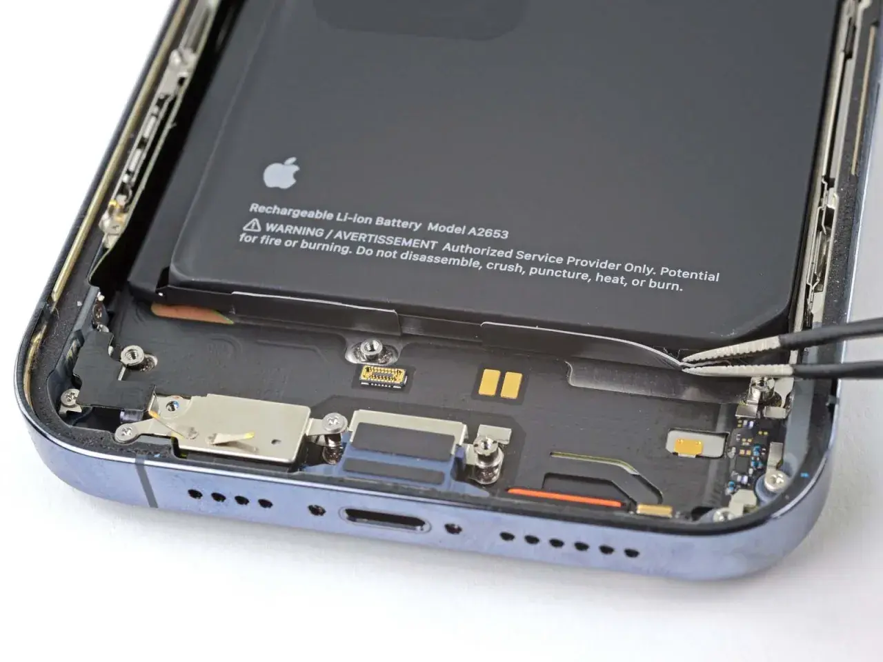 Wymiana baterii iPhone 14 Pro w toku. Pęseta odłącza taśmę baterii.