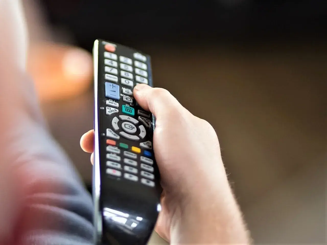 Dłoń trzyma pilot, zastanawiając się, czy telewizję naziemną można oglądać przez internet.