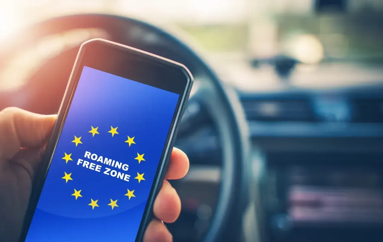 Telefon z flagą UE i napisem "ROAMING FREE ZONE". Podróżując po UE, nie trzeba włączać roamingu.