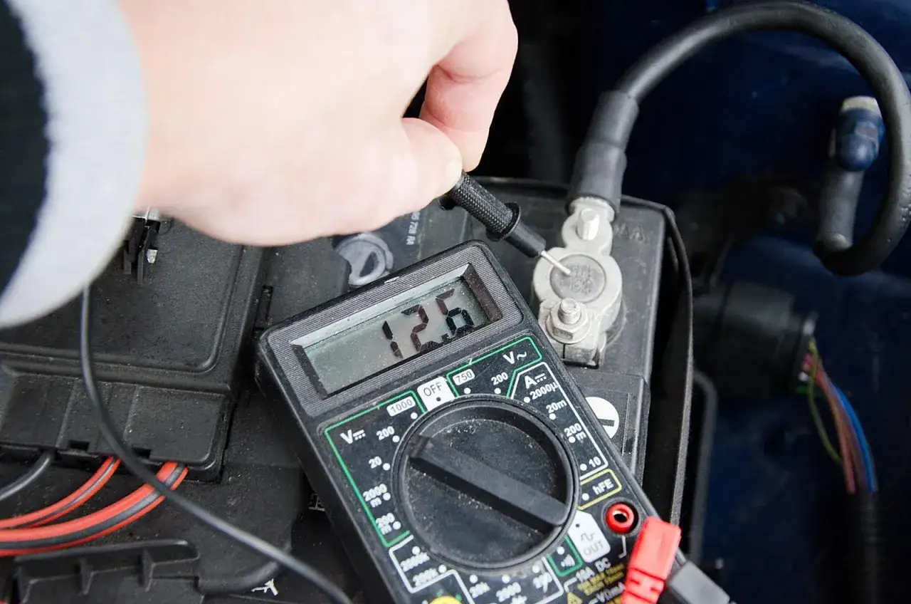 Sprawdzanie napięcia akumulatora multimetrem. Wynik 12.6V wskazuje na dobry stan.
