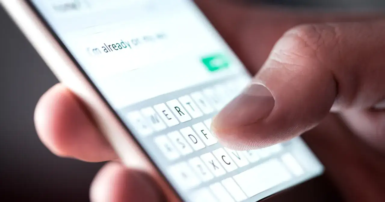 Kciuk pisze wiadomość na telefonie, korzystając z klawiatury RCS.