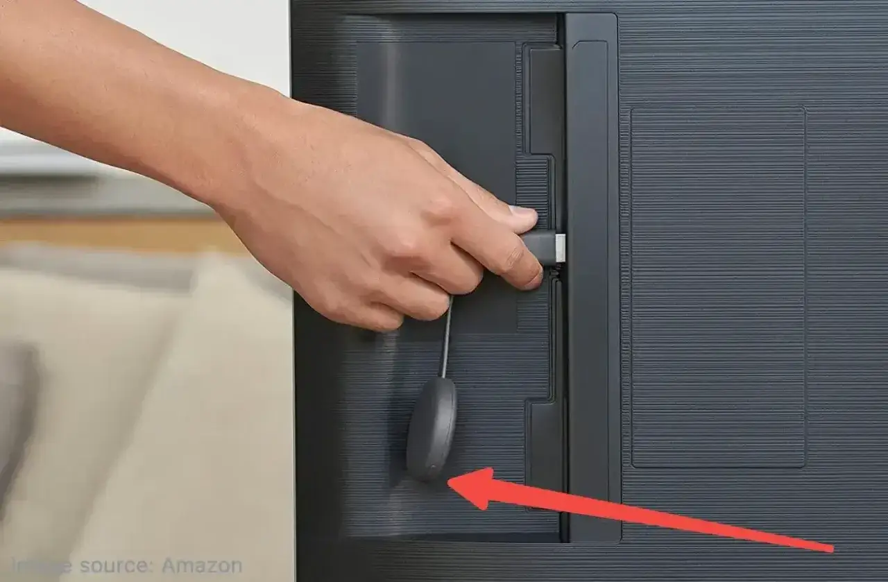Dłoń podłącza Chromecast do telewizora. Aby jak zresetować Chromecast, naciśnij i przytrzymaj przycisk na urządzeniu.