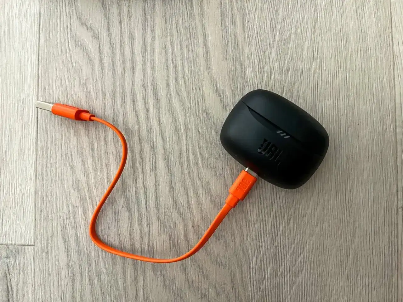 Czarny futerał słuchawek JBL z pomarańczowym kablem USB-C. Dowiedz się, jak podłączyć słuchawki JBL do telefonu.